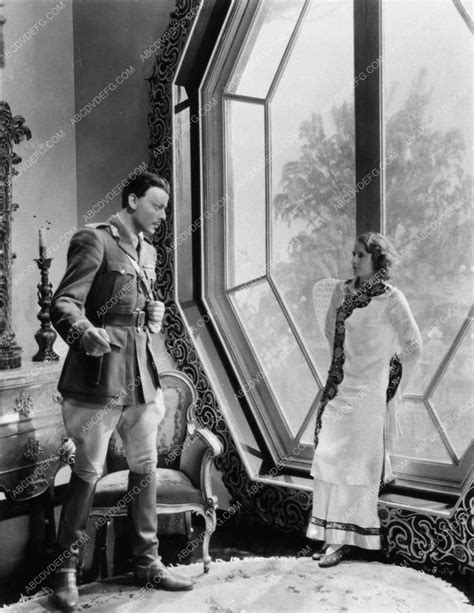 An Old Black And White Photo Of Two People Standing In Front Of A Large Window