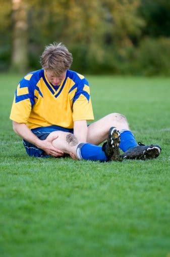 Soccer Player Is Injured And Sitting On The Field Stock Photo