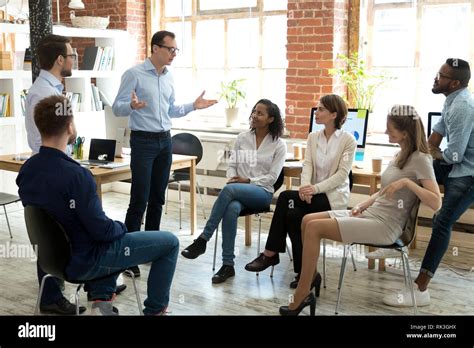 Diverse Employees Listening To Male Manager Speaking At Group Meeting