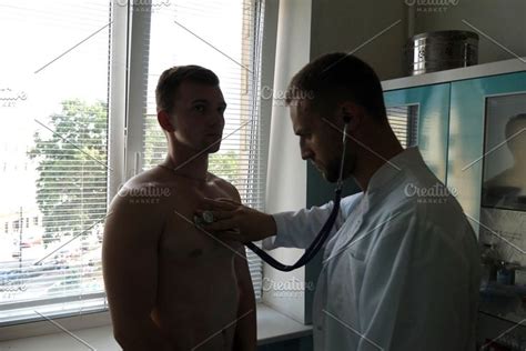 Doctor Examining Young Male Patient With Stethoscope Medic Checking Chest Of Guy In Her Office