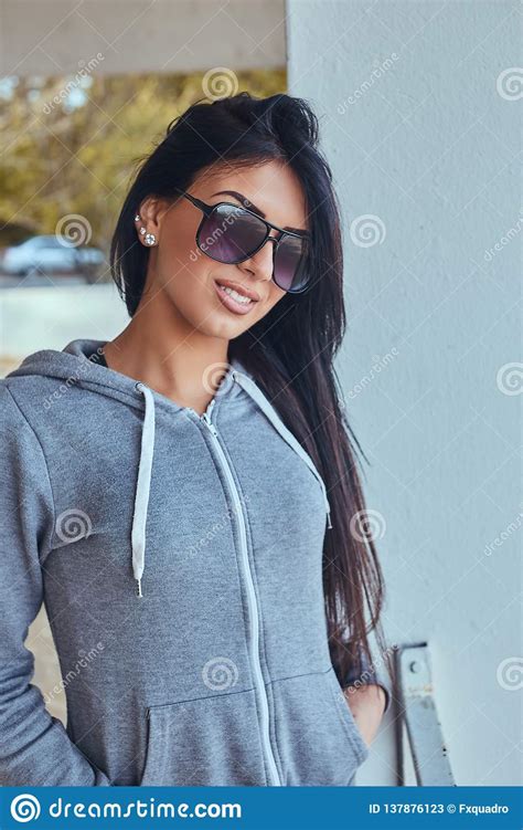 Portrait Of A Beautiful Girl With Tanned Skin Wearing A Gray Hoodie And