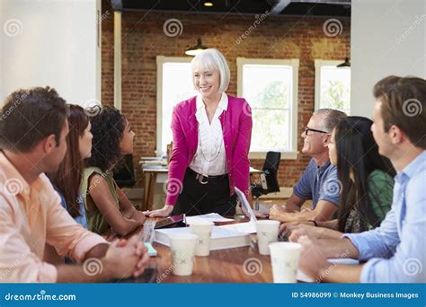 Senior Female Boss Addressing Office Workers At Meeting Stock Image