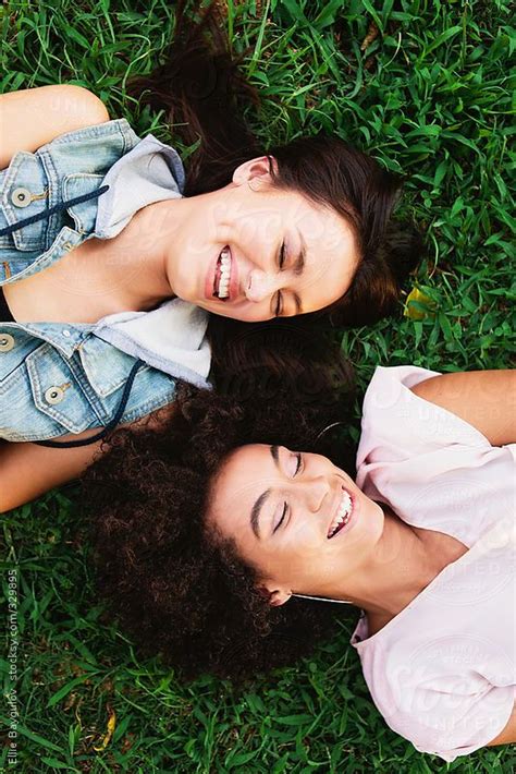Two Laughing Girls Laying On The Grass By Stocksy Contributor Ellie Baygulov Portrait