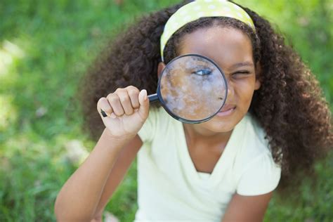 Young Girl Looking Through Magnifying Glass In The Park On A Sunny Day