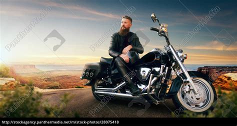 Biker Sitting On His Chopper And Looks On Sunset Stock Photo