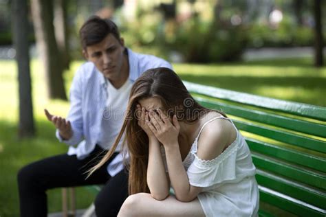 Sad Young Girl Crying During Conflict With Her Boyfriend On Bench At