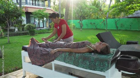 asian woman massage therapist doing massage to girl on the beach summer vacation on luxury spa