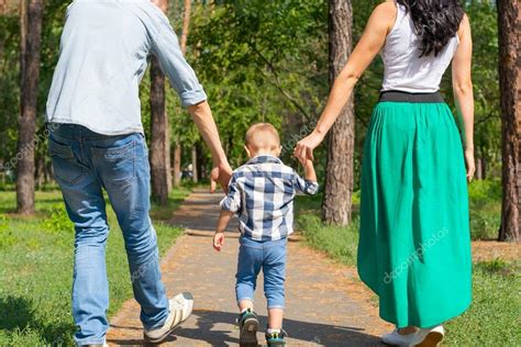 Papá Y Mamá Sostienen A Su Hijo De La Mano Y Caminan Por El Parque R 2023
