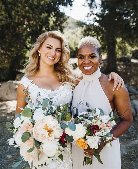 Two Women Standing Next To Each Other With Bouquets In Their Hands And