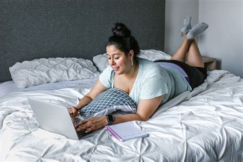 Curvy Latin Woman Lying On Bed Using Computer In Latin America Plus