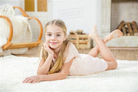 Cute Little Girl Lying On White Carpet And Smiling At
