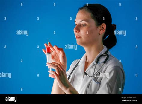 A Young Female Nurse Holding A Syringe Filled With Red Liquidmodel