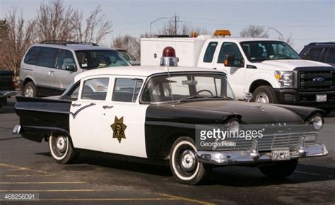 A Vintage 1950s Ford Black And White Police Car Is Parked At The