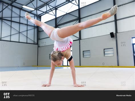 rear view of teenage caucasian female gymnast performing at sports hall doing handstand and