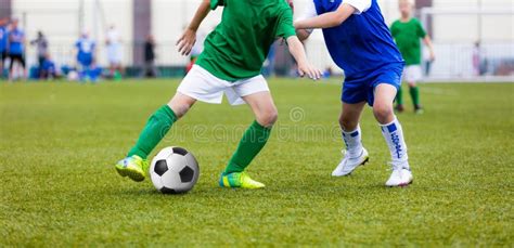 Young Boys Playing Football Soccer Game On Sports Field Running Stock