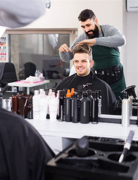 Male Hairdresser Doing Haircut For Male Client At Hair Salon Stock