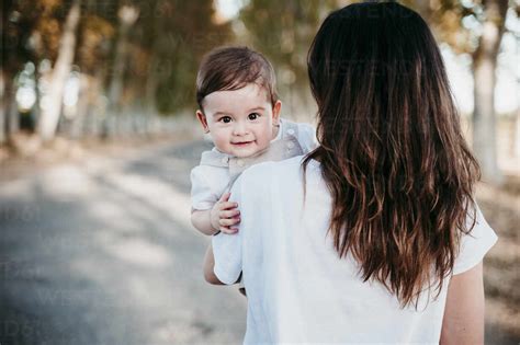 Mother Carrying Baby Boy While Standing On Road Outdoors Stock Photo
