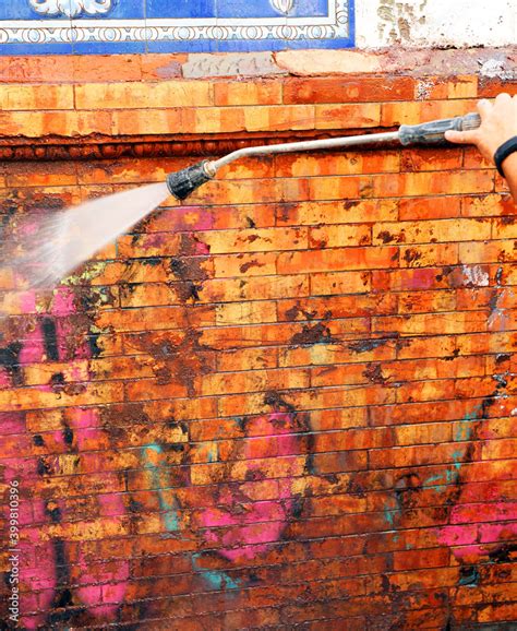 Worker Cleaning Graffiti In A Dirty Facade With High Pressure Water