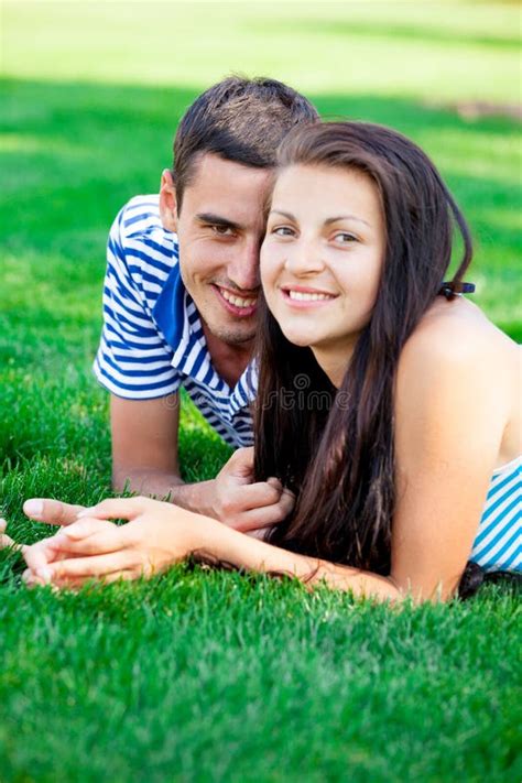 Photo Of Cute Couple Smiling And Lying On The Grass In The Field Stock