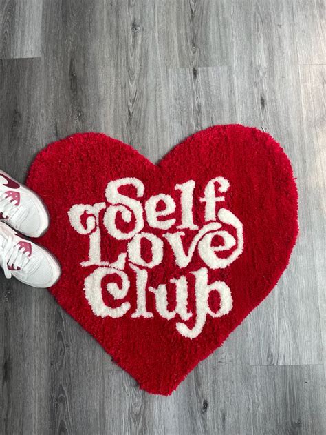Someone Is Standing On The Floor In Front Of A Heart Rug That Says Self Love Club