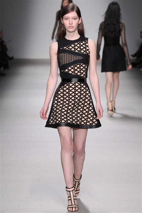 a model walks down the runway in a black and white dress with cutouts on it