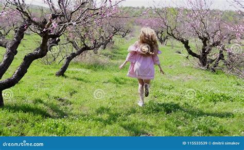 In The Garden Of Flowering Trees Runs Blonde In Pink Dress Stock Video