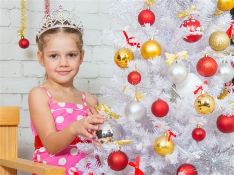 Girl Hangs Balls On A Snowy New Years Christmas Tree Stock Photo