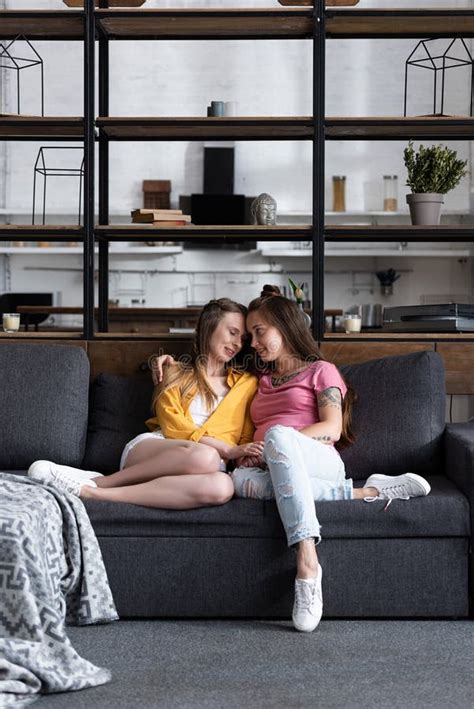 Two Pretty Lesbians Embracing While Sitting On Sofa In Living Room Stock Image Image Of