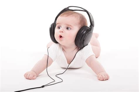 Encantador Bebé En Un Blanco Con Auriculares Escuchando Música Foto