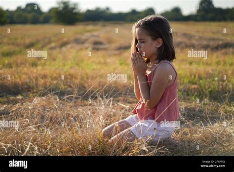 Little Girl Closed Her Eyes Praying In A Field Hands Folded In Prayer