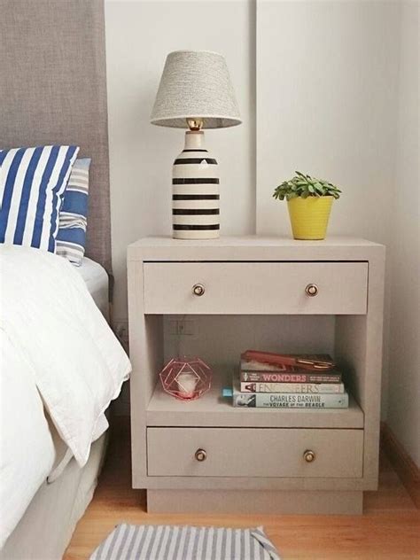 A Nightstand With A Lamp And Books On It In A Bedroom Next To A Bed