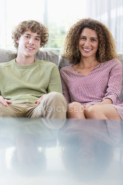 Portrait Of Happy Mother And Son Sitting On Couch In Living Room