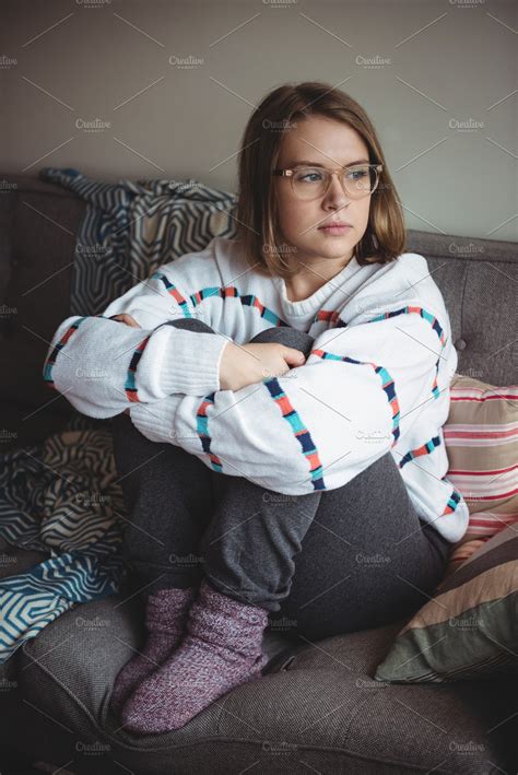Thoughtful Woman Sitting And Hugging Her Knees In Living Room High