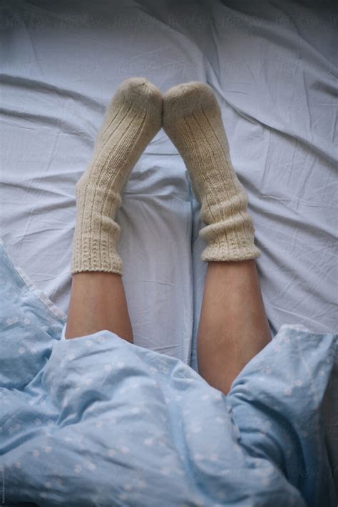 female legs in cosy winter socks under the sheet on the bed by stocksy contributor mak stocksy