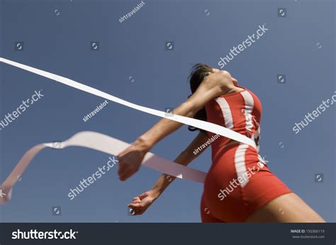 Low Angle View Of Young Female Athlete Crossing Finish Line Against