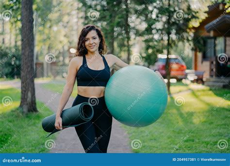 Sport And Recration Concept Pleased Slim Brunette Woman Wears Cropped Top And Leggings Holds