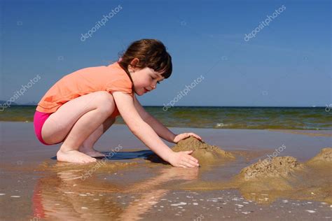 niños en la playa chica joven jugando en la arena para hacer castillos de arena fotografía de