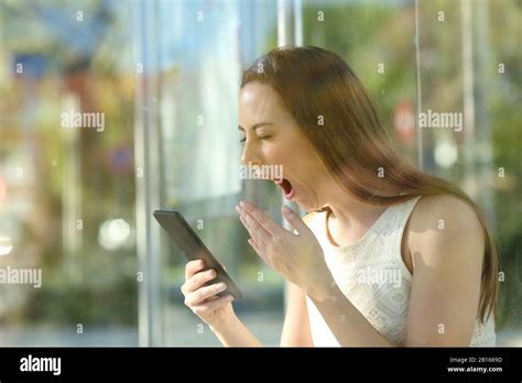 Tired Woman Yawning Checking Mobile Phone Sitting At Bus Stop Waiting