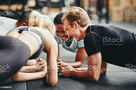 Smiling Gym Friends Planking Together During A Workout Class Stock