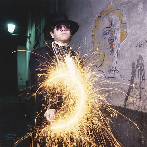 A Man In A Hat And Glasses Holding A Sparkler With His Hands While