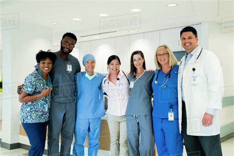Portrait Of Cheerful Doctors And Nurses Standing In Hospital Corridor