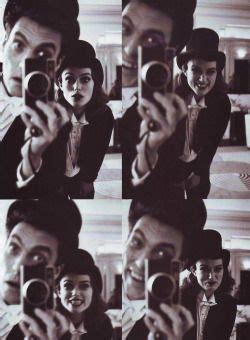 Black And White Photograph Of Woman Taking Selfie In Mirror With Man