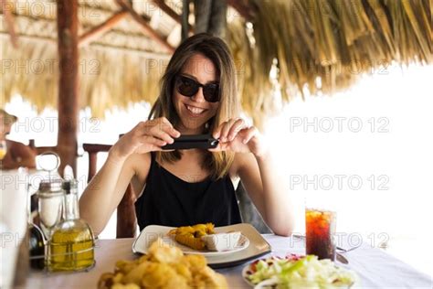 Woman By Table Using Phone Photo12 Tetra Images