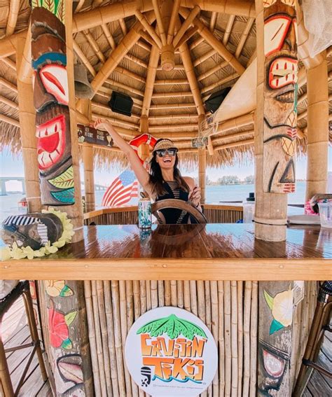 a woman sitting on top of a wooden bar with tiki decorations above her head