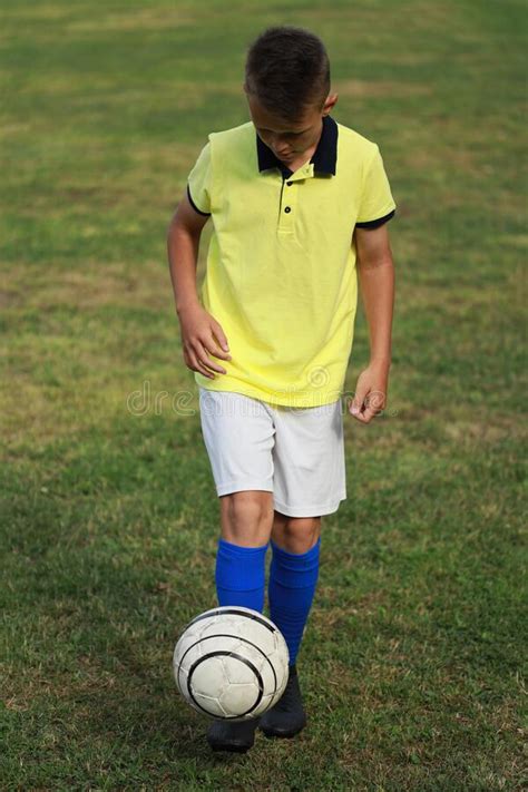 Boy Soccer Player In A Yellow T Shirt On The Soccer Field Juggles The