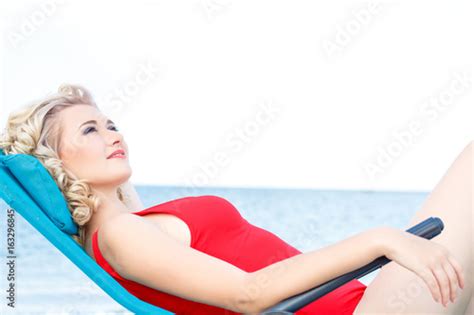 Beautiful Blonde In A Red Swimsuit Lies On A Deckchair Rest On The Sea