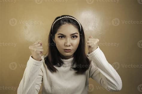 beautiful asian girl is mad and angry with arms fist isolated on orange background 7352926
