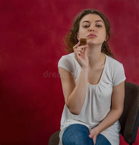 Woman Holds A Piece Of Chocolate In Her Hands Sitting On A Chair Red