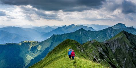 Two Hikers Walking On A Grassy Mountain Ridge Hiking Atop The Grassy