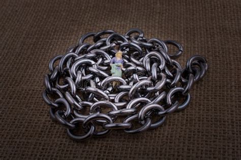 Woman Figurine On Steel Chains On A Textured Surface Stock Image